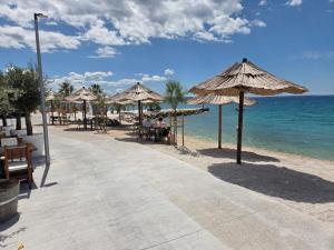 a beach with tables and umbrellas and the ocean at Beach Hotel Božikovina in Podstrana