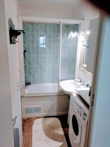 y baño con bañera, lavabo y lavadora. en Appartement 2 pièces pour 4 personnes avec vue mer, en Saint-Hilaire-de-Riez