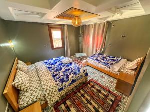a bedroom with two beds and a rug at Tabourihte Gardens in Tinerhir