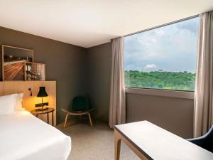 a hotel room with a bed and a large window at Pullman Sao Paulo Guarulhos Airport in Guarulhos