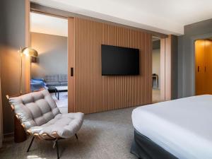 a hotel room with a bed and a chair and a television at Pullman Sao Paulo Guarulhos Airport in Guarulhos