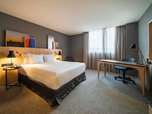 a hotel room with a large bed and a desk at Pullman Sao Paulo Guarulhos Airport in Guarulhos