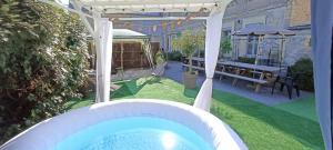 une cour avec un bain à remous et une pergola dans l'établissement Séjour familial haut de gamme spa et confort près des plages du Débarquement, à Sommervieu