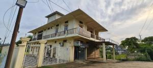 a white house with a balcony and a fence at Protibha Homestay in Sibsāgar