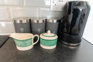 three coffee cups sitting on a counter next to a coffee maker at Comfortable Stays - Shirley, Solihull in Birmingham