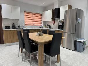 a kitchen with a wooden table and black chairs at Lola Apartment in Marsaskala in Marsaskala