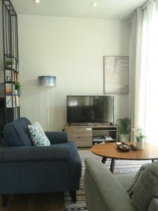a living room with a blue couch and a tv at Little Garden private pool villa in Al Ḩamrāʼ +35 photos