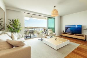 Una sala de estar con un sofá y un televisor. en Bayline Algarve Apt – Beachfront, Spa, Lagoon View, en Armação de Pêra