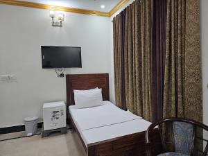 a small bedroom with a bed and a tv at Butt Lodges 2 in Islamabad