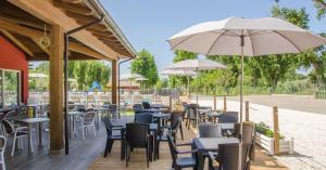 an outdoor restaurant with tables and chairs and umbrellas at Camping Trasimeno in Passignano sul Trasimeno