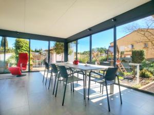 a dining room with a table and chairs and large windows at Les Pieds dans Thau in Marseillan
