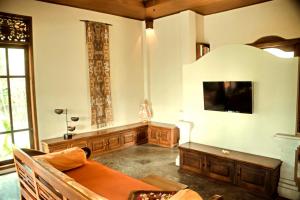 a living room with a couch and a tv on the wall at Villa Tunjung- 3BR, infinity pool, staff in Mayong