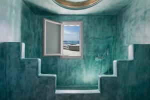 Baño verde con ventana y escalera en Villa Irini Fira - Adults Only, en Fira