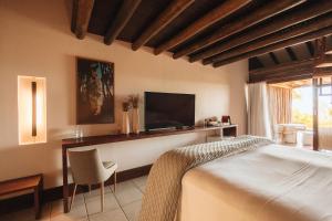 a bedroom with a bed and a tv and a chair at Pousada Maravilha in Fernando de Noronha