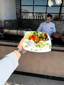 a person holding up a plate of food at King house hotel dahab in Dahab