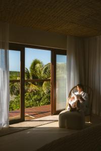a woman sitting in a chair in a room with a window at Pousada Maravilha in Fernando de Noronha