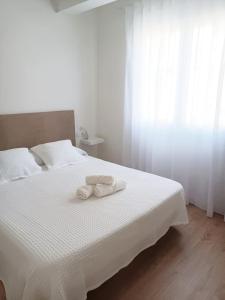 a bedroom with a white bed with two towels on it at AREAS NEGRAS- Apartamento centro de Cedeira. in Cedeira +22 photos