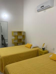 a room with two beds with yellow sheets at Paraiso Pitimbu in Pitimbu