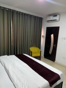 a bedroom with a large bed and a yellow chair at Crystal homes 1 in Lekki
