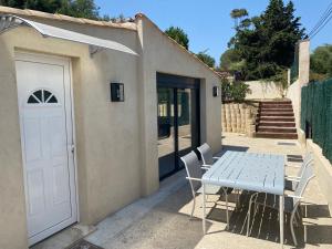 a table and chairs next to a white door at GRIMAUD-Maison 4 Pers - Piscine in Grimaud