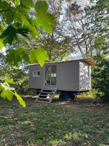 a tiny house sitting on top of a field at La roulotte du Manoir 1900 in La Ferté-Gaucher