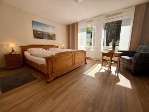 a bedroom with a wooden bed and a couch and windows at Ferienhaus Blinkfuer in Neuharlingersiel