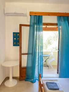 a bedroom with blue curtains and a table and a window at Studio Pavlos in Dassia