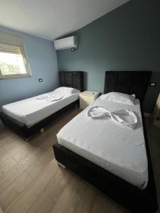 two twin beds in a room with a window at FOUR L's in Arape-Rashbulli