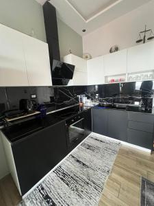 a kitchen with black and white cabinets and a wooden floor at FOUR L's in Arape-Rashbulli