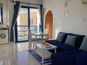 a living room with a blue couch and a table at paphos pool view gem - cozy 1 bed Apartment in Paphos