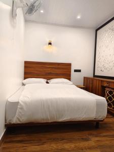 a bedroom with a large bed with a wooden headboard at Birdwing Cottage, Munnar in Munnar +14 photos