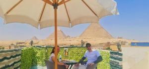 Un uomo e una donna seduti a un tavolo sotto un ombrello di pyramids show inn a Il Cairo