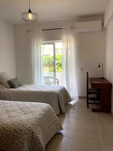 a bedroom with two beds and a desk and a window at Apt H - Beach Village in Olhos de Água