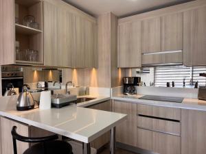 une cuisine avec des armoires en bois et un comptoir blanc dans l'établissement Edificio Claro Solar - Moderno Apartamento Centro Temuco 2D2B Parking, à Temuco