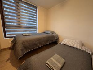 une chambre avec deux lits et une grande fenêtre dans l'établissement Edificio Claro Solar - Moderno Apartamento Centro Temuco 2D2B Parking, à Temuco