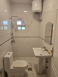 a white bathroom with a toilet and a sink at Malath Furnished Units-ملاذ للوحدات المفروشة 2 in Tabuk