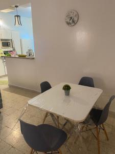 a white table with chairs and a clock on the wall at Maison El Omrane 2 in Bin Rhilouf
