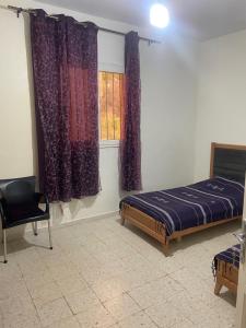 a bedroom with a bed and a window and a chair at Maison El Omrane 2 in Bin Rhilouf +5 photos