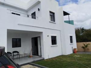 a white house with a patio in front of it at Kalyan Villa in Pointe aux Piments
