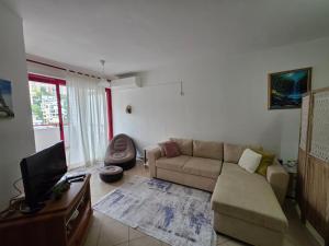 a living room with a couch and a tv at Volga Cozy Apartment in Durrës