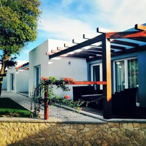 a house with a pergola in front of it at Charming House Atalaia + Pool in Lourinhã