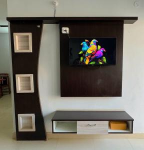 Una sala de estar con un televisor en la pared. en Vista Royale Greens 104 2bhk, en Patna