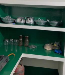 a green shelf with pots and pans on it at Protibha Homestay in Sibsāgar