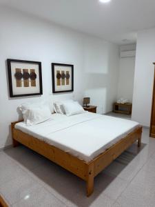 a large bed in a room with two pictures on the wall at Pousada Praia Maria in Praia