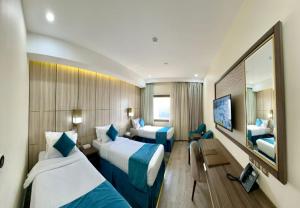 a hotel room with two beds and a television at Al Ebaa Hotel in Mecca
