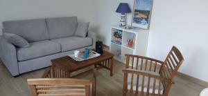 Una sala de estar con un sofá, una mesa y sillas. en Maisons de Saint Guenolé, en Batz-sur-Mer