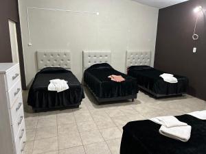 3 camas en una habitación con sábanas negras en Depto XL Villa Unión, en Villa Unión