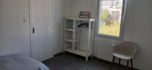 Un dormitorio con una cama y una silla y una ventana. en Maisons de Saint Guenolé, en Batz-sur-Mer