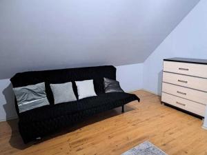 Un sofá negro en una habitación con una cómoda. en Dom na Złotnikach, en Skorka