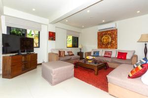 Una sala de estar con un sofá y un televisor. en Naiharn beach sands Apartment, en Nai Harn Beach